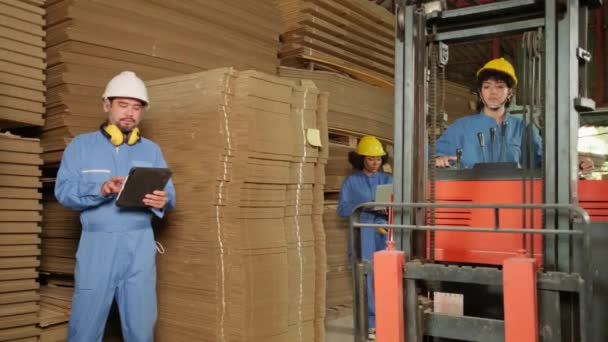 業界の工場労働者チームは ラップトップによる保管 倉庫での在庫注文 フォークリフトで段ボールを積み上げる管理杭 製品ロジスティクスを製造しています — ストック動画