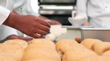 Şeflerin elini kapayarak beyaz aşçı üniformaları ve önlükleri hamur hamurunu yoğuruyor, ekmek, kek, kek ve taze fırında pişiriyor, restoranın paslanmaz çelik mutfağında fırında pişiriyor..