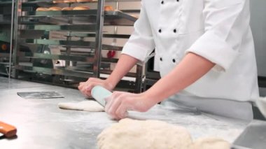 Şefin elini kapayarak, önlüklü beyaz aşçı üniformalarıyla hamur işlerini rulo ile yoğuruyor, ekmek, turta ve taze fırın yemekleri hazırlıyor, restoranın paslanmaz çelik mutfağında fırında pişiriyorlar..