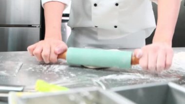 Şefin elini kapayarak, önlüklü beyaz aşçı üniformalarıyla hamur işlerini rulo ile yoğuruyor, ekmek, turta ve taze fırın yemekleri hazırlıyor, restoranın paslanmaz çelik mutfağında fırında pişiriyorlar..