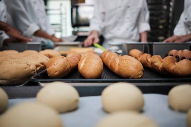 Baget ekmeğine yakın çekim ve beyaz üniformalı şeflerin önünde leziz ekmek yeme hamur yoğurma, taze fırın yemeği hazırlama, restoran mutfağında fırında pişirme..