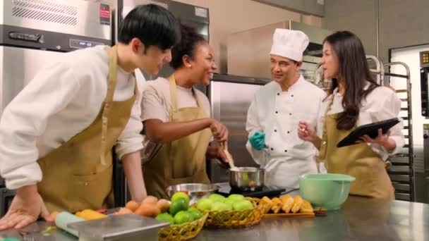 趣味の料理コース 料理の制服の上級男性シェフは ペストリー料理のための材料を準備し 混合し 攪拌する若い料理クラスの学生を教えて レストランのステンレス鋼のキッチンで果物パイ — ストック動画