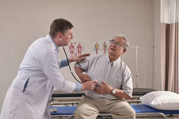 Üniformalı Beyaz Erkek Doktor Steteskoplu Yaşlı Hastayı Hastane Koğuşundaki Acil — Stok fotoğraf