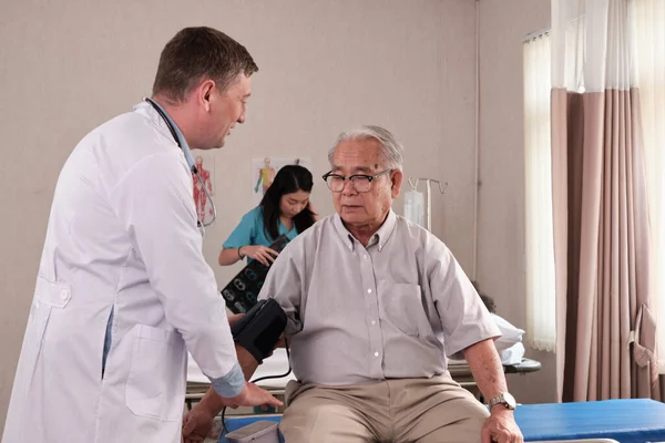 Kaukaski Lekarz Mundurowych Badaniach Stanu Zdrowia Starszy Pacjent Ciśnienie Krwi — Zdjęcie stockowe