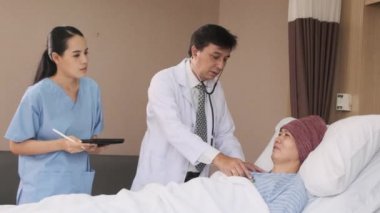 Üniformalı profesyonel doktorlar Asyalı erkek hastayı steteskopla kontrol ediyor, hastane koğuşundaki yatağında ilaç tedavisi görüyor, tıbbi klinik, kanser muayenesi....
