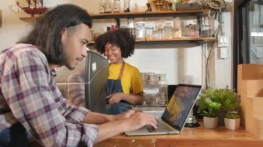 İki kafe işletme ortağı ve arkadaşları, Afro-Amerikan kadın ve Taylandlı erkek barmenler kahve dükkanının tezgahında birlikte neşeli bir gülümseme, mutlu servis işi ve KME girişimcisi.