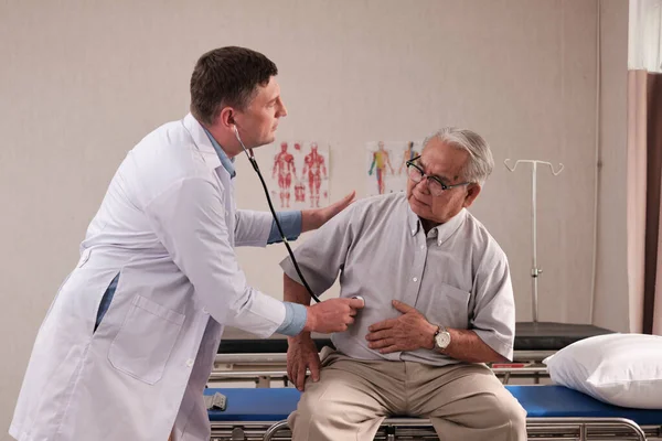 Üniformalı Beyaz Erkek Doktor Steteskoplu Yaşlı Hastayı Hastane Koğuşundaki Acil — Stok fotoğraf