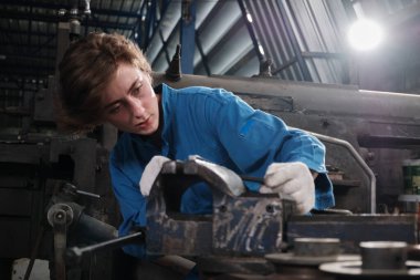 Profesyonel bir kadın mühendis güvenlik üniforması içinde çalışıyor. Metal işçiliği hassas aletleri, mekanik torna makineleri ve çelik fabrikasında yedek parça atölyesi var..