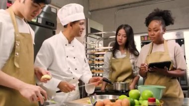 Hobi mutfak kursu, aşçı üniforması giyen kıdemli aşçı genç aşçılık sınıfı öğrencilerine elma soymayı ve doğramayı öğretiyor. Hamur işleri için malzemeler, paslanmaz çelik mutfakta meyveli turtalar..