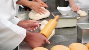 Şeflerin elini kapayarak beyaz aşçı üniformaları ve önlükleri hamur hamurunu yoğuruyor, ekmek, kek, kek ve taze fırında pişiriyor, restoranın paslanmaz çelik mutfağında fırında pişiriyor..