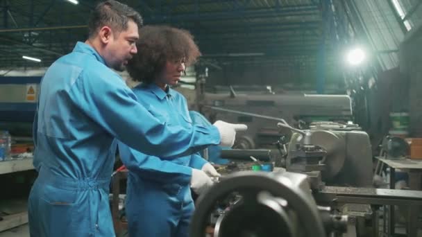 两名专业的工业工程师合作伙伴穿着安全制服在钢厂工作 配有精密金属加工工具 机械车床和零配件车间 — 图库视频影像