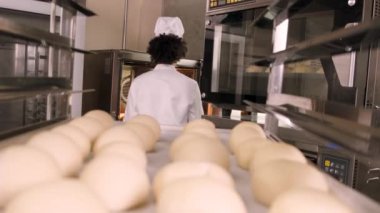 Beyaz önlüklü, şapkalı, hamur işlerinden ekmek yapan, taze fırın yemekleri hazırlayan, restoranın paslanmaz çelik mutfağında fırında pişiren profesyonel Afro-Amerikan kadın aşçı..