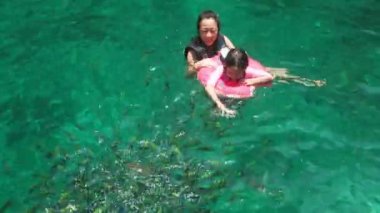 Pembe mayo ve can simidi içinde Asyalı turistler anne ve çocuk zümrüt denizde yüzmenin keyfini çıkarıyorlar. Phi Phi Adası 'nda bir sürü palyaço balığı var. Yaz tatillerinde gezen bir aile..