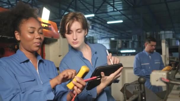 機械の電圧電流を検査し 製造工場で点検し 維持することにより 安全制服を着た2人のプロの女性技術者が働く 電気システムサービスの職業 — ストック動画