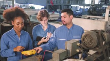 Güvenlik üniformalı çok ırklı profesyonel mühendislik ekipleri, makinelerin voltaj akımlarını kontrol ederek, kontrol ederek ve fabrikada, elektrik sistemi işlerinde çalışırlar..