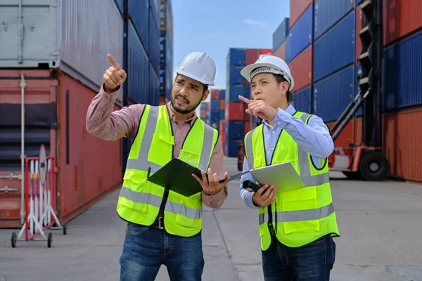 两名身穿安全制服和头戴硬礼帽的亚洲男性专业人员在一个拥有许多集装箱的物流码头工作 为货物运输行业装载控制航运货物 — 图库照片