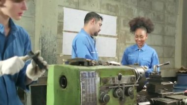 Güvenlik üniforması giyen iki profesyonel endüstri çalışanı ve mühendis ortakları metal iş araçlarıyla çalıştılar, torna makinelerinin mekanik çizimini tartıştılar ve imalathanede atölye çalışmalarını tartıştılar..