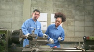 Güvenlik üniforması ve mühendis ortağı olan iki profesyonel endüstri çalışanı hassas metal işçiliği araçlarıyla çalıştı ve fabrikadaki torna atölyesindeki makine atölyesinin mekanik çizimini tartıştılar..