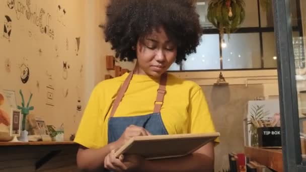 アフリカ系アメリカ人女性のスタートアップ バリスタがカジュアルなカフェのドアに立ち 看板に書いて コーヒーショップのサービス仕事で楽しく明るい笑顔で そして新しいビジネス起業家を見せてくれます — ストック動画