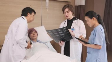 Üniformalı doktorlar röntgen filmlerini tartışıyor, Asyalı iyileşme hastalarına hastane koğuşundaki yataklı odada yatan erkek hastalara, tıbbi kliniğe, kanser muayenesine,.