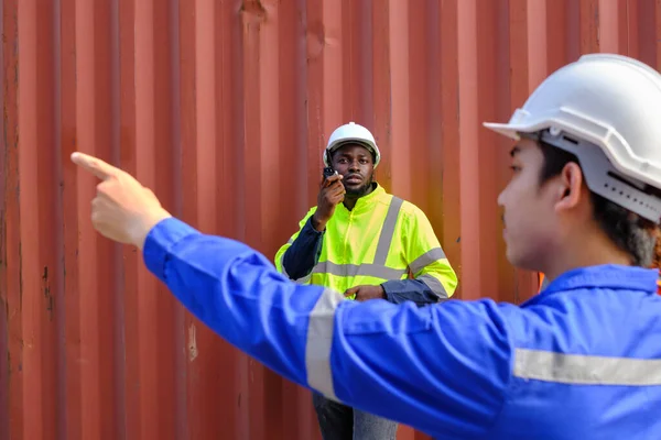 身着安全制服的非裔美国和亚裔男性员工使用对讲机 在集装箱背景下的物流终端指挥工作 控制航运货物和货物运输行业 — 图库照片