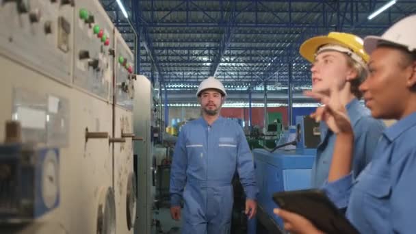 ハード帽子と安全制服の多人種専門産業エンジニアチームは 機械製造工場 電気サービス職業で機械制御パネルを検査し 点検し 維持する — ストック動画