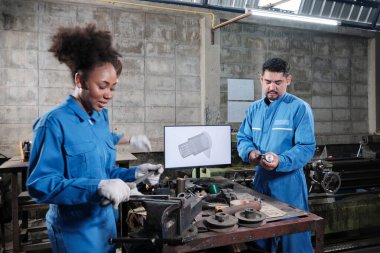 Üç çok ırklı profesyonel endüstri mühendisi güvenlik üniformalı işçiler metal işçiliği işleri bir monitör, torna makineleri ve imalat fabrikasında atölye ile mekanik çizim tartışır.