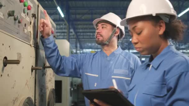 ハード帽子と安全制服を着たプロの業界エンジニアチームは 機械製造工場 電気サービス職業のタブレットで機械の制御パネル メンテナンスチェックを検査します — ストック動画