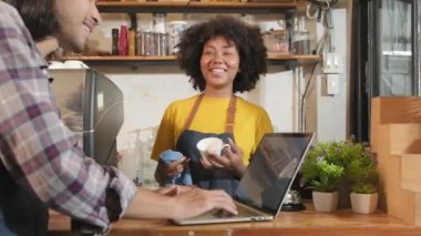 İki kafe işletme ortağı ve arkadaşları, Afro-Amerikan kadın ve Taylandlı erkek barmenler kahve dükkanının tezgahında birlikte neşeli bir gülümseme, mutlu servis işi ve KME girişimcisi.