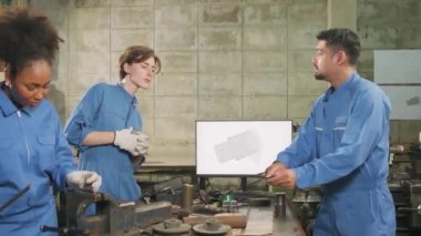 Üç çok ırklı profesyonel endüstri mühendisi güvenlik üniformalı işçiler metal işçiliği işleri bir monitör, torna makineleri ve imalat fabrikasında atölye ile mekanik çizim tartışır.