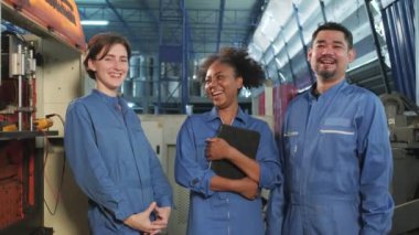 Güvenlik üniformalı çok ırklı endüstri çalışanları iş başarısından sonra rahatlar ve birlikte gülerler, mutluluğu gülümseyerek ifade ederler ve mekanik fabrikada neşelidirler. Profesyonel mühendis mesleği.