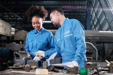 Güvenlik üniforması ve mühendislik ortakları giyen iki profesyonel endüstri çalışanı metal iş araçlarıyla çalıştı, torna makineleri için mekanik hassasiyeti ve imalat fabrikasındaki atölyeleri kontrol etti..