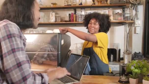 アフリカ系アメリカ人女性とタイ人男性のバリスタがコーヒーショップのカウンターバー ハッピーサービスの仕事 中小企業の起業家で一緒に会話し 明るい笑顔 — ストック動画