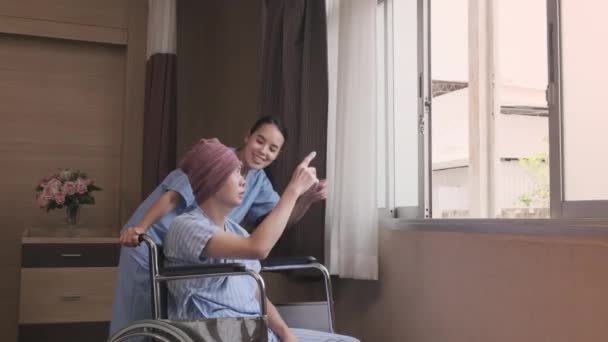 身穿制服的年轻亚洲女医生鼓励轮椅男病人在窗口支持和激励康复 在医院病房接受化疗后得癌症 — 图库视频影像