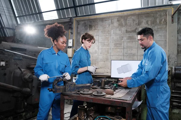 Three multiracial professional industry engineer workers teams in safety uniforms metalwork jobs discuss with mechanical drawing in a monitor, lathe machines, and workshop in manufacturing factory.