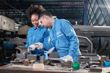 Güvenlik üniforması ve mühendislik ortakları giyen iki profesyonel endüstri çalışanı metal iş araçlarıyla çalıştı, torna makineleri için mekanik hassasiyeti ve imalat fabrikasındaki atölyeleri kontrol etti..