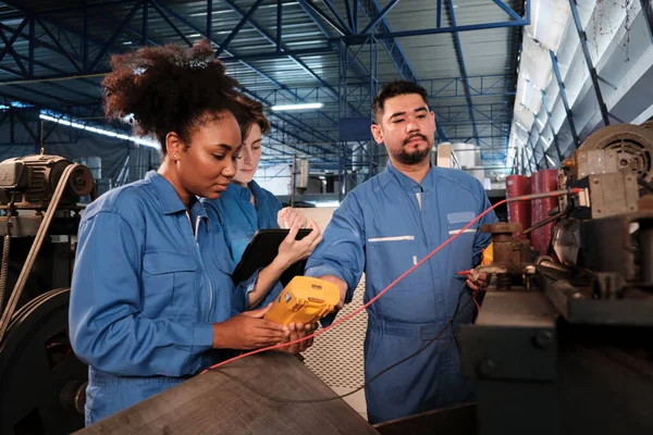 Multiracial professional industry engineer teams in safety uniforms work by inspecting machines\' voltage current, checking, and maintaining at manufacture factory, electric system service occupations.