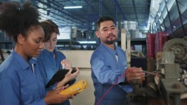 Güvenlik üniformalı çok ırklı profesyonel mühendislik ekipleri, makinelerin voltaj akımlarını kontrol ederek, kontrol ederek ve fabrikada, elektrik sistemi işlerinde çalışırlar..