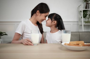 Sağlıklı Asya Tayland ailesi, mutlu küçük kız ve genç anne yemek masasında birlikte taze süt ve ekmekle birlikte, sağlıklı beslenme kahvaltısı, sabah yaşam tarzı.