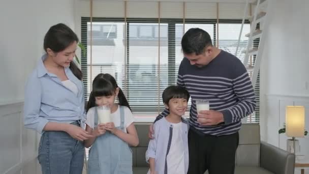 幸せな健康的なタイの家族 小さなアジアの兄弟は 朝の若いお母さんとお父さんと一緒に新鮮な牛乳を飲み 笑顔と喜びを素敵な家で一緒に ウェルネス栄養 国内の朝食ライフスタイル — ストック動画