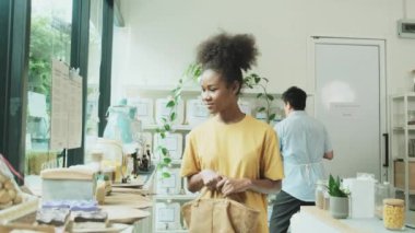 Young African American woman is choosing and shopping for organic products in refill store with reusable bag, zero-waste grocery, and plastic-free, eco environment-friendly, sustainable lifestyles.