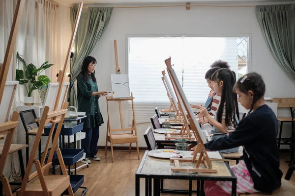 一名亚洲女教师在美术教室的画布上向孩子们教授和示范丙烯酸彩绘 在小学工作室教育中创造性地学习技巧 — 图库照片