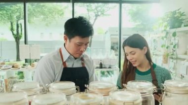 İki esnaf, yeniden kullanılabilir konteynırlardaki doğal organik ürünlerin stoklarını kontrol ediyor. Sıfır atık, plastiksiz bakkal ve çevre dostu, sürdürülebilir yaşam tarzları..