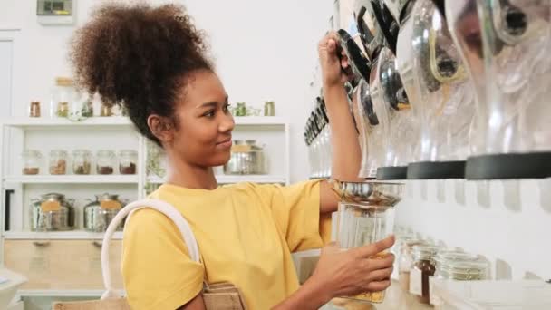 非裔美国女性顾客将谷物食品装在玻璃瓶中 将可重复使用的容器放在再装箱中 零废物和无塑料食品 环境友好 可持续的生活方式 — 图库视频影像