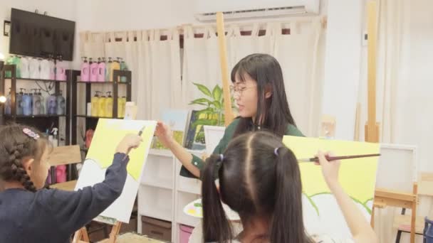 Азійська Вчителька Викладає Демонструє Дітям Акриловий Кольоровий Живопис Полотні Класі — стокове відео
