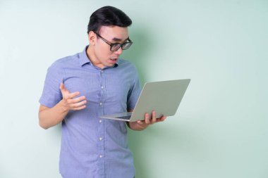 Genç Asyalı işadamı yeşil arka planda poz veriyor