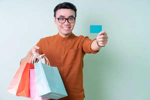 Joven Hombre Asiático Sosteniendo Bolsa Compras Sobre Fondo Verde —  Fotos de Stock