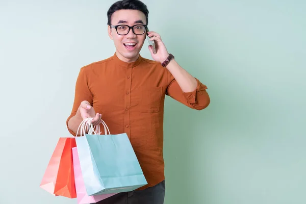 Joven Hombre Asiático Sosteniendo Bolsa Compras Sobre Fondo Verde —  Fotos de Stock