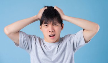 Genç Asyalı adam mavi arka planda poz veriyor