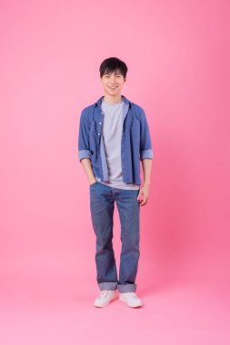 Genç Asyalı adam pembe arka planda poz veriyor.
